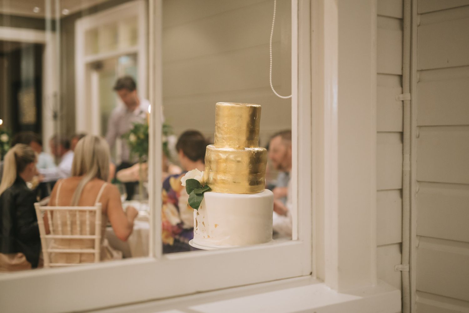 A golden tiered wedding cake fountain sits in front of a window at an elegant reception venue.