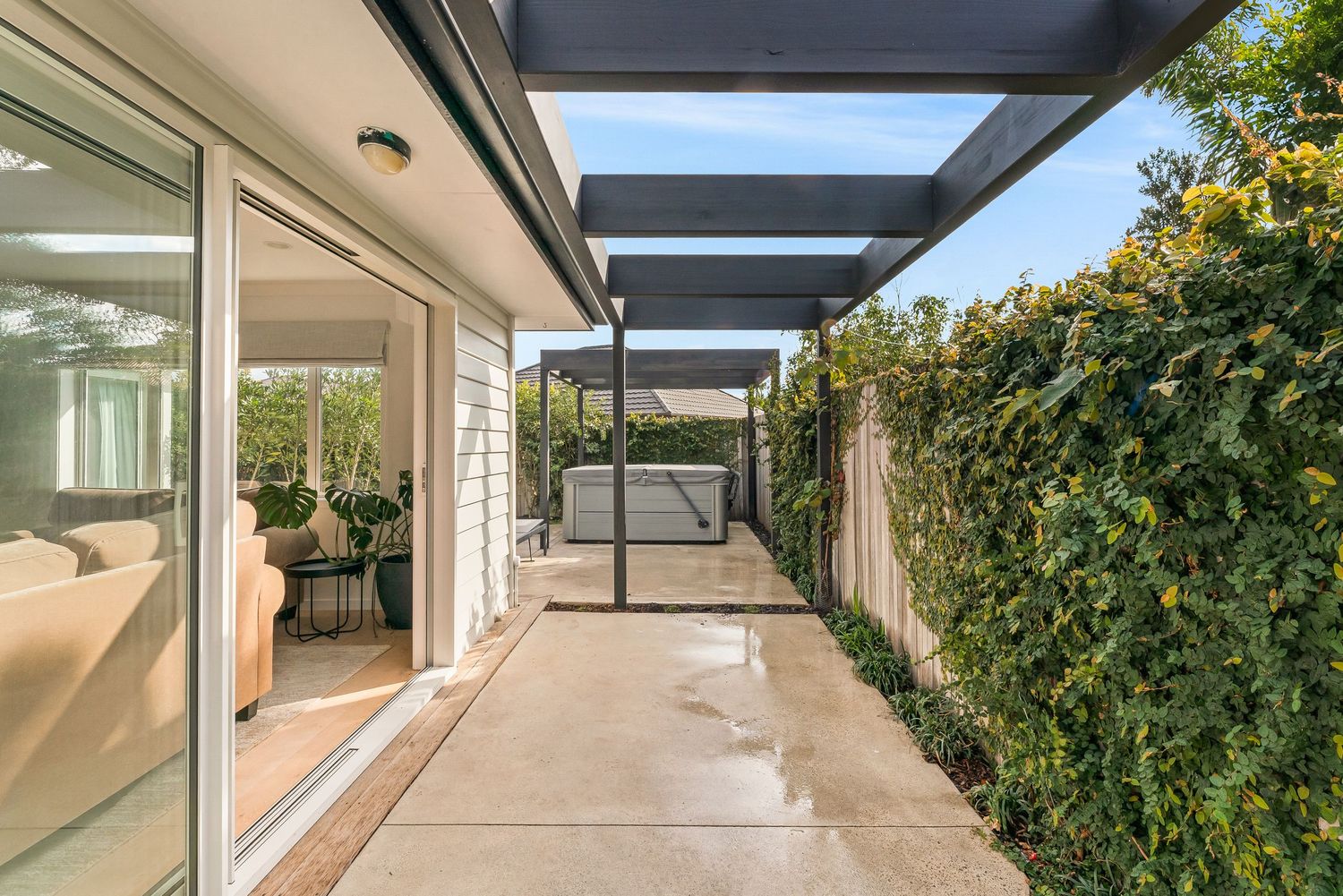 Covered walkway with dark pergola beams connecting different sections of the modern home.