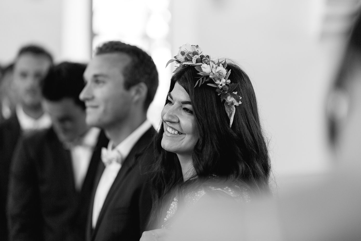 Black and white photograph capturing candid emotional reactions during wedding ceremony in church setting.