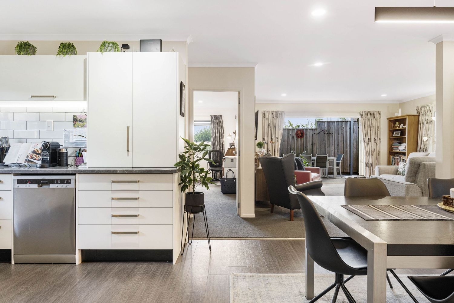 Modern open concept kitchen and living area with white cabinets, wood flooring and contemporary furniture.