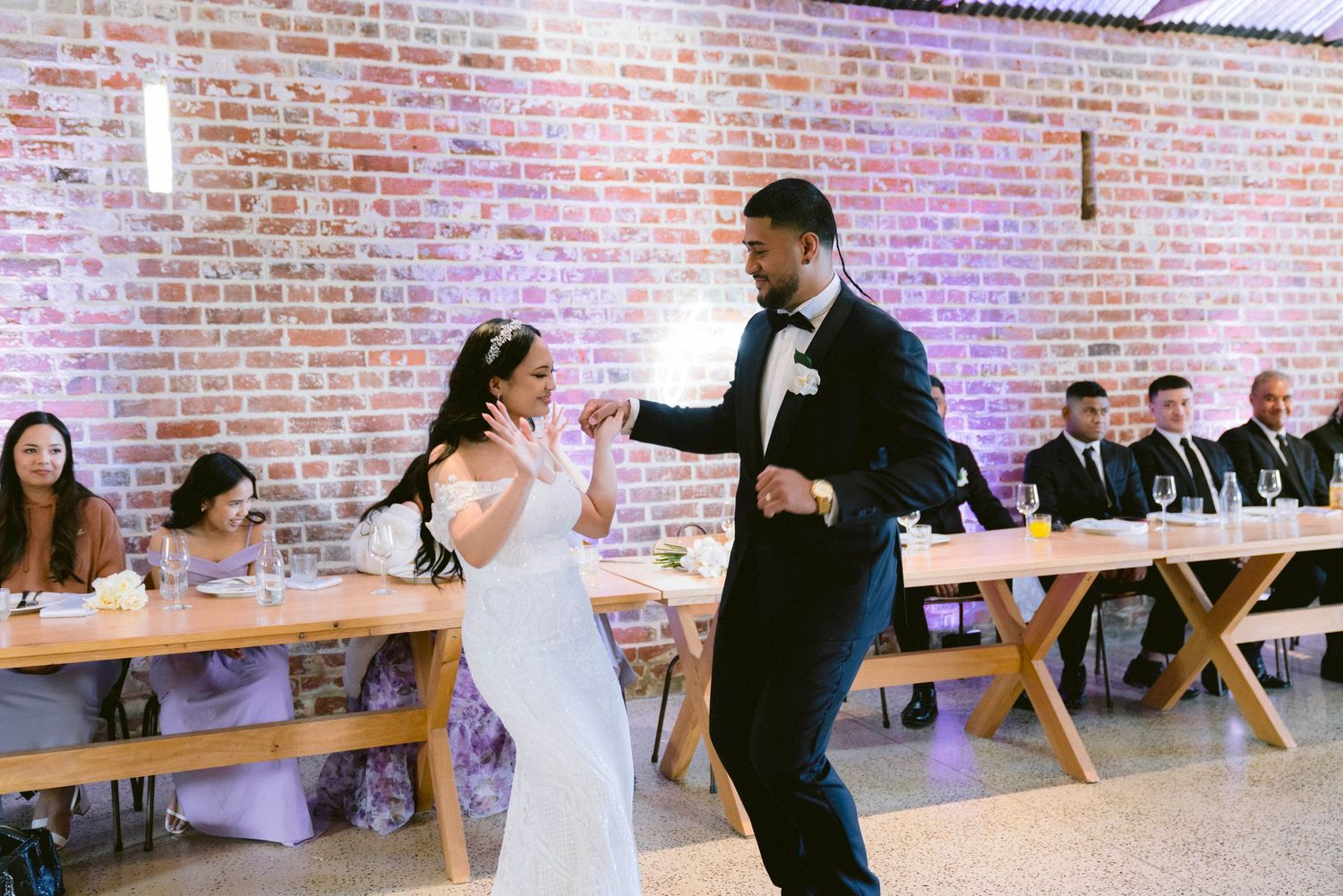 Couple dancing together at wedding reception in rustic brick venue.