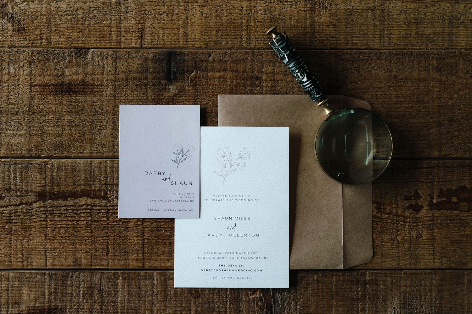 Rustic wooden surface displaying wedding invitations and decorative elements against a textured background.