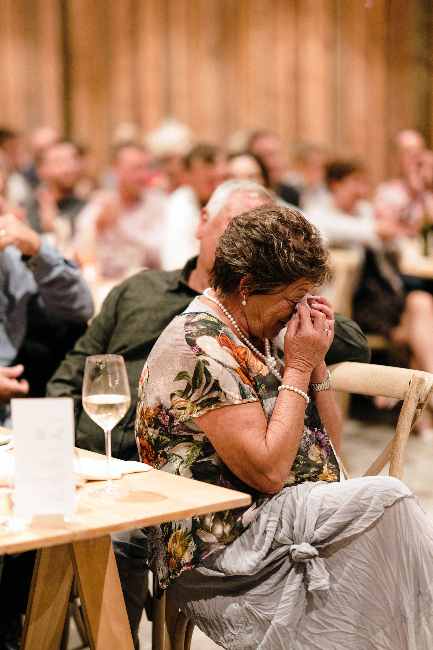 Guest at wedding reception showing emotional reaction during speeches.