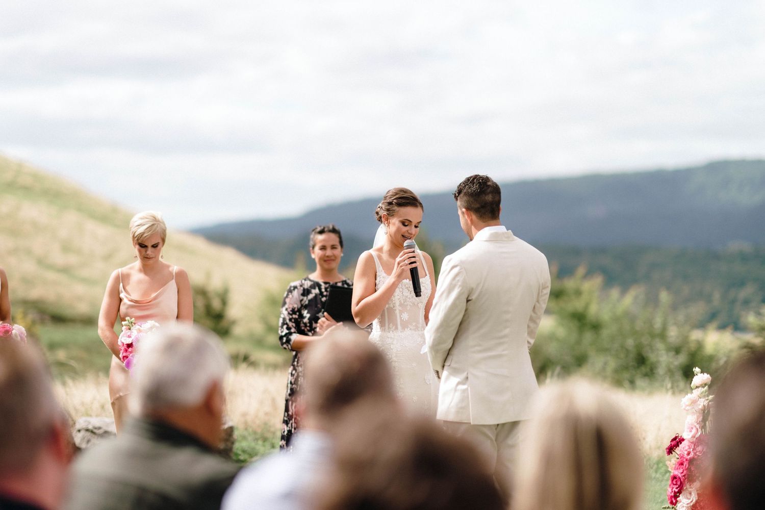 Scenic mountain wedding ceremony overlooking valley with attendees.