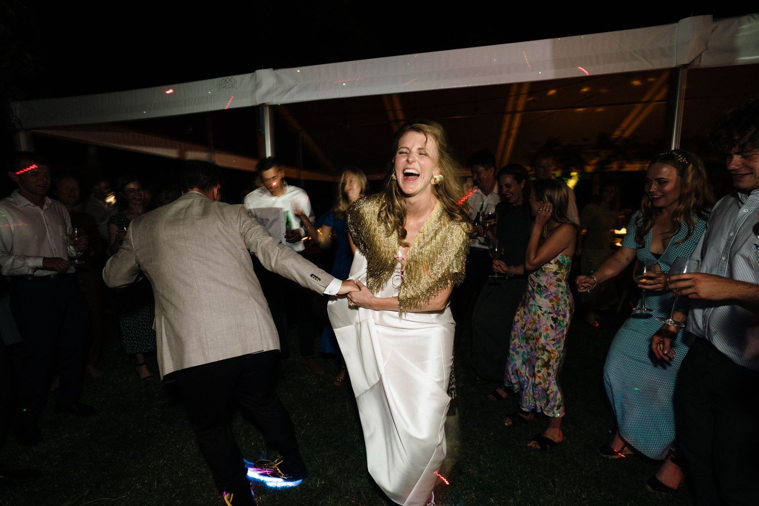 People dancing and celebrating at a nighttime party with dramatic lighting.