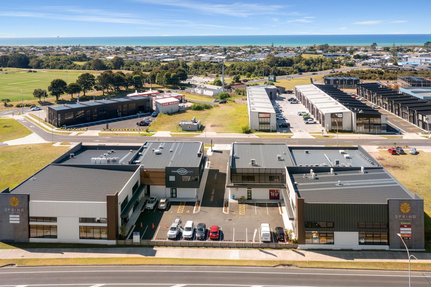 Aerial view of commercial buildings and parking lots in a suburban business park on a sunny day.