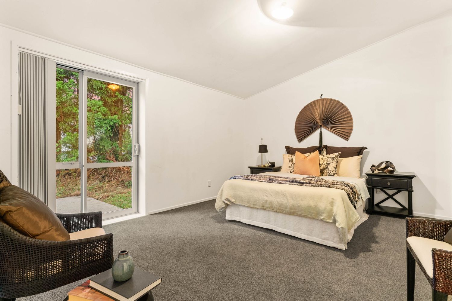 Spacious bedroom with plush carpet, large windows, and neutral color scheme.