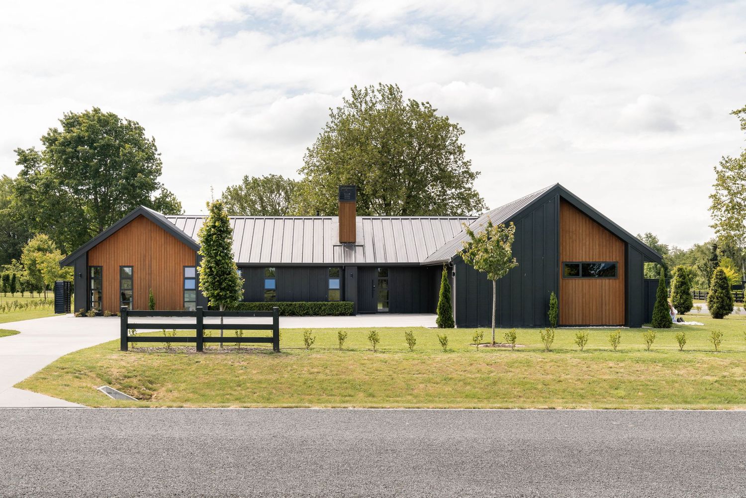 Modern barn-style homes with metal roofs and dark exterior finishes along a country road.