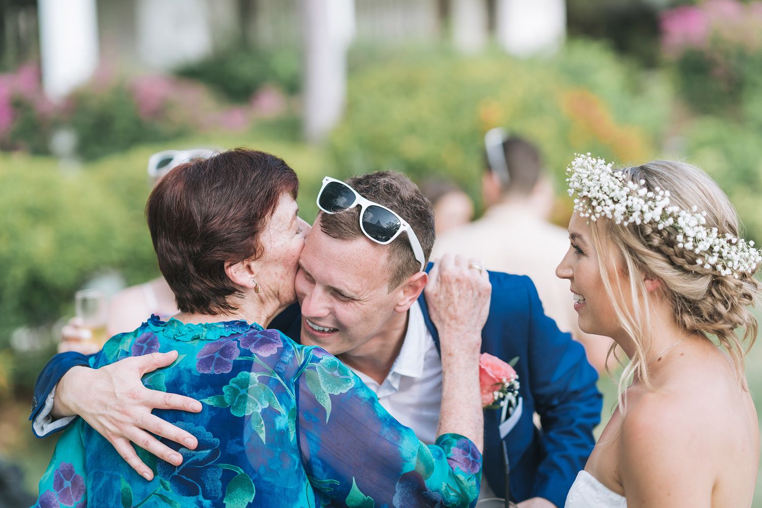 Wedding guests sharing emotional embraces during outdoor celebration.