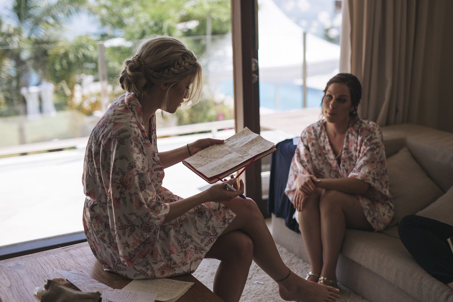 Two individuals sit together in a warmly lit space beside a window creating an intimate atmosphere.