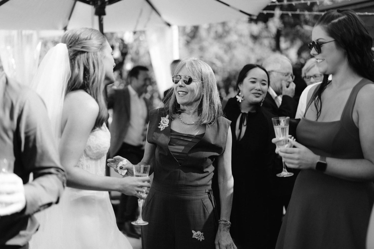 People gathered at a wedding reception hold drinks and socialize at a celebratory event.
