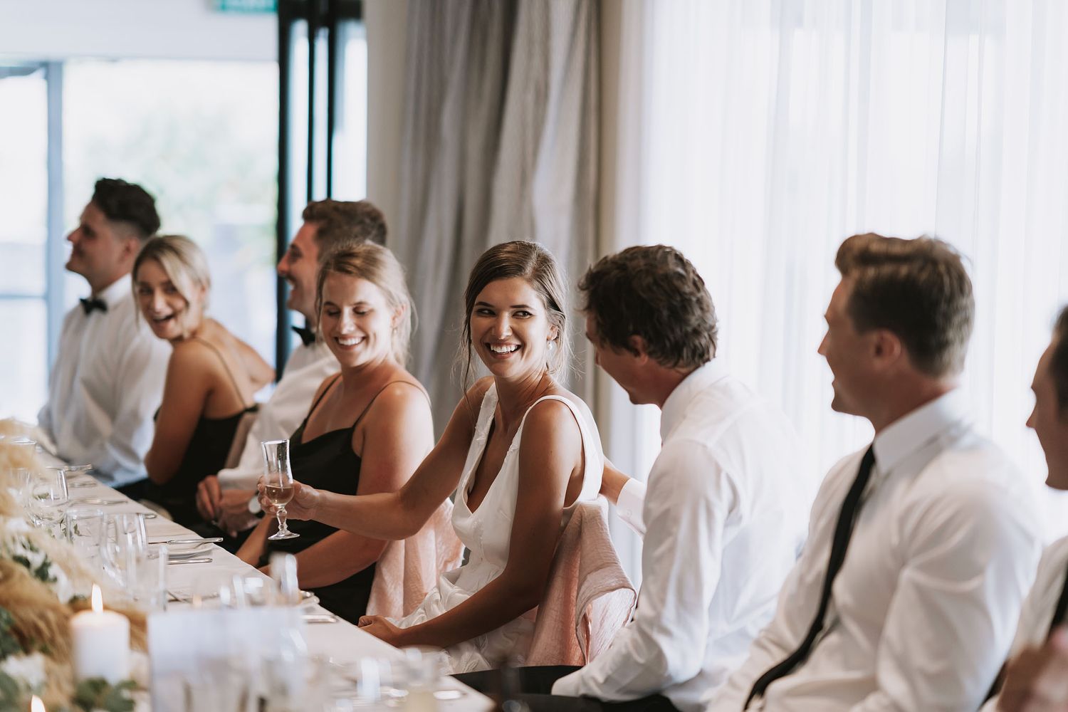 Bridal party laughs together during candid moments at a wedding reception celebration.