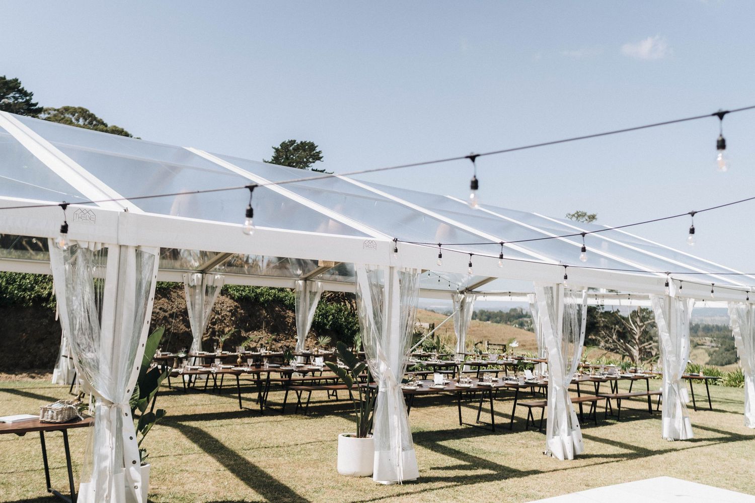 White wedding tent with string lights set up in an outdoor venue for a celebration.