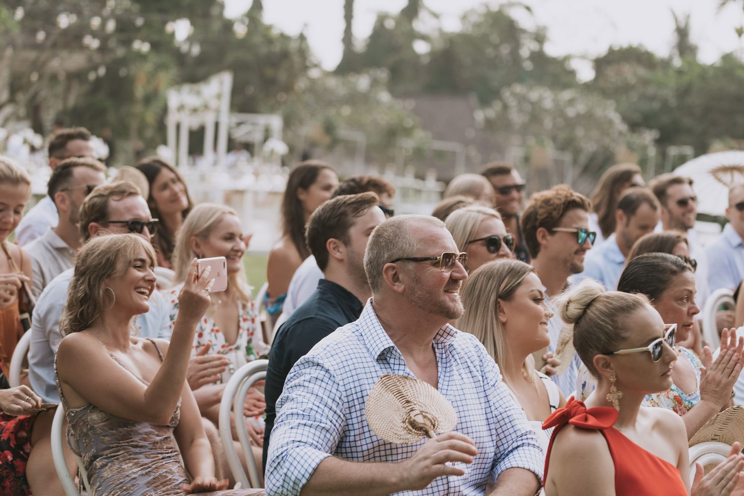 Wedding guests smile and applaud during an emotional ceremony moment.