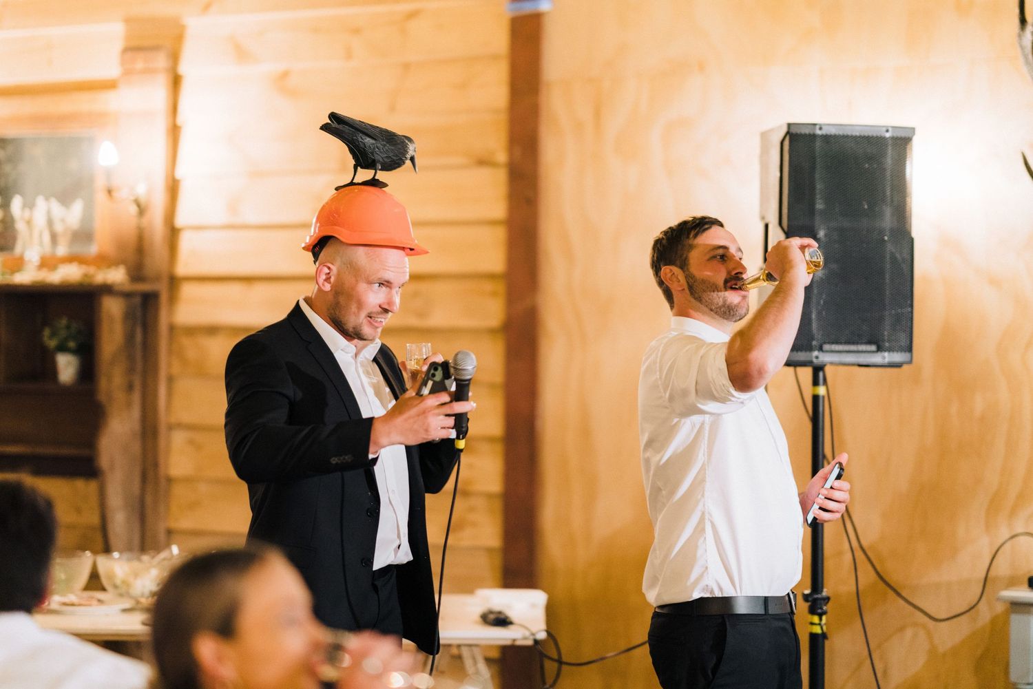 Wedding reception guests celebrate in a warm wooden interior with vintage lighting.