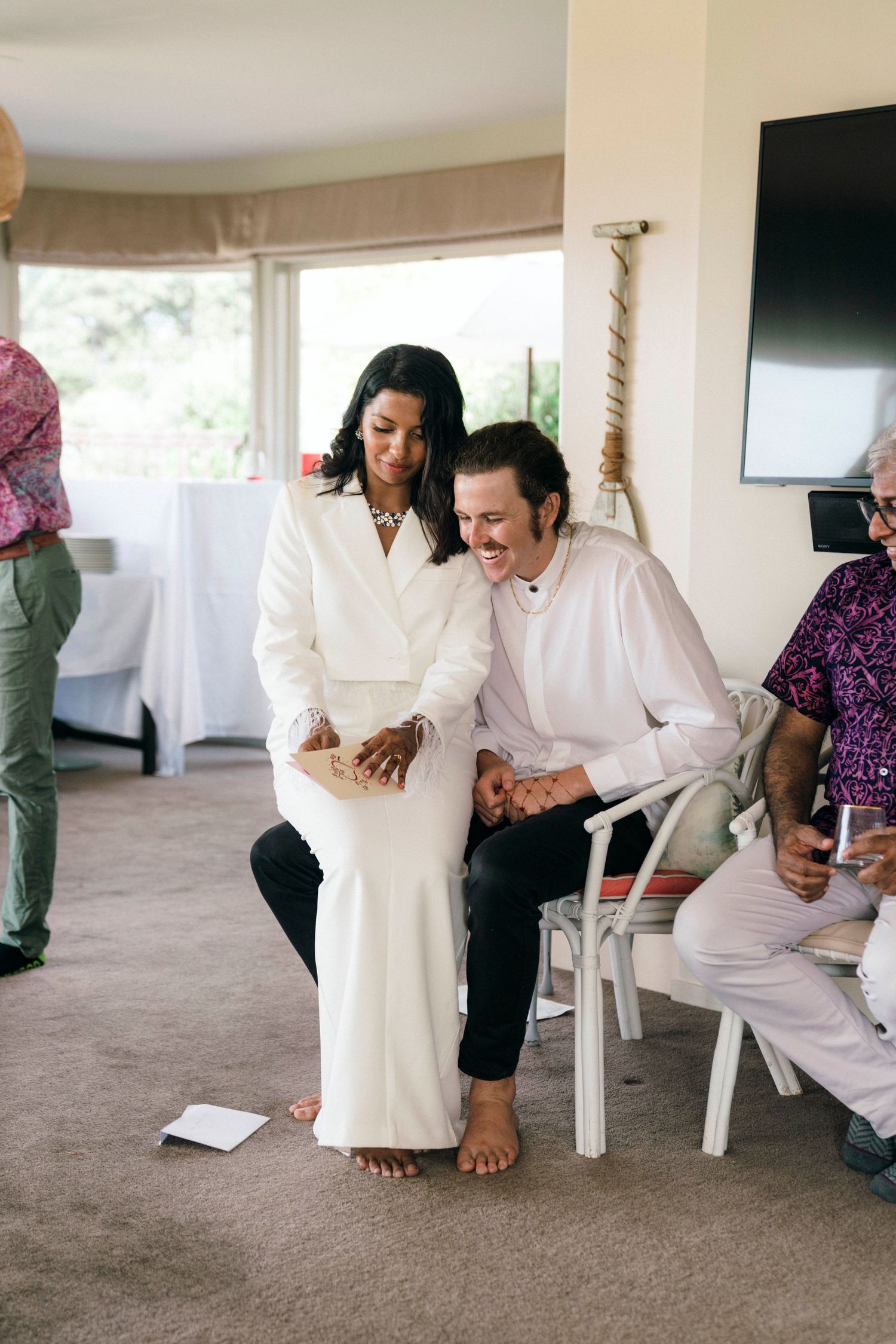 A couple shares an intimate moment while sitting together indoors during their wedding celebration.