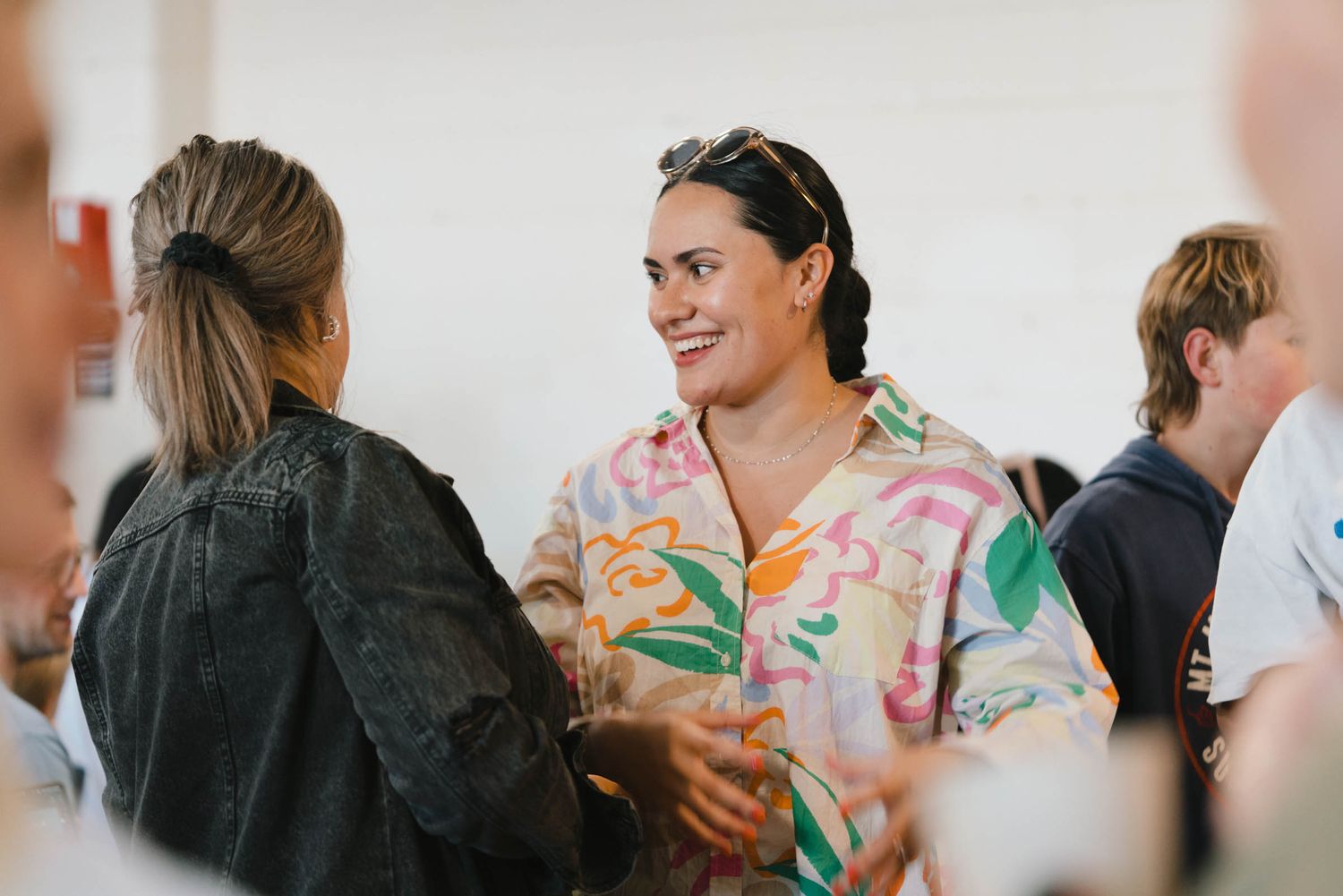 Group of people engaged in conversation at an indoor gathering.