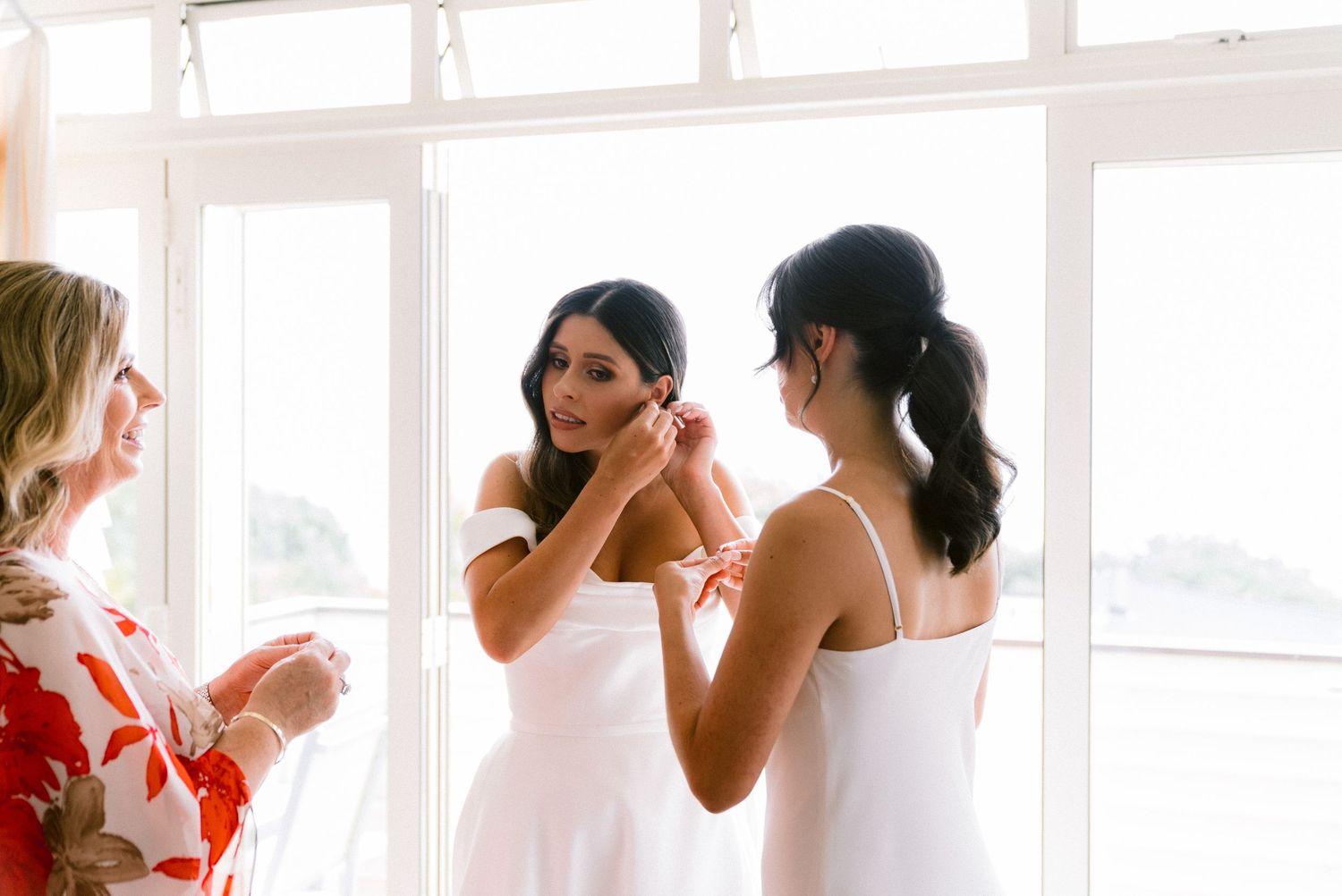 A series of five photos showing people getting ready at a bright window-lit venue with bridesmaid dresses.