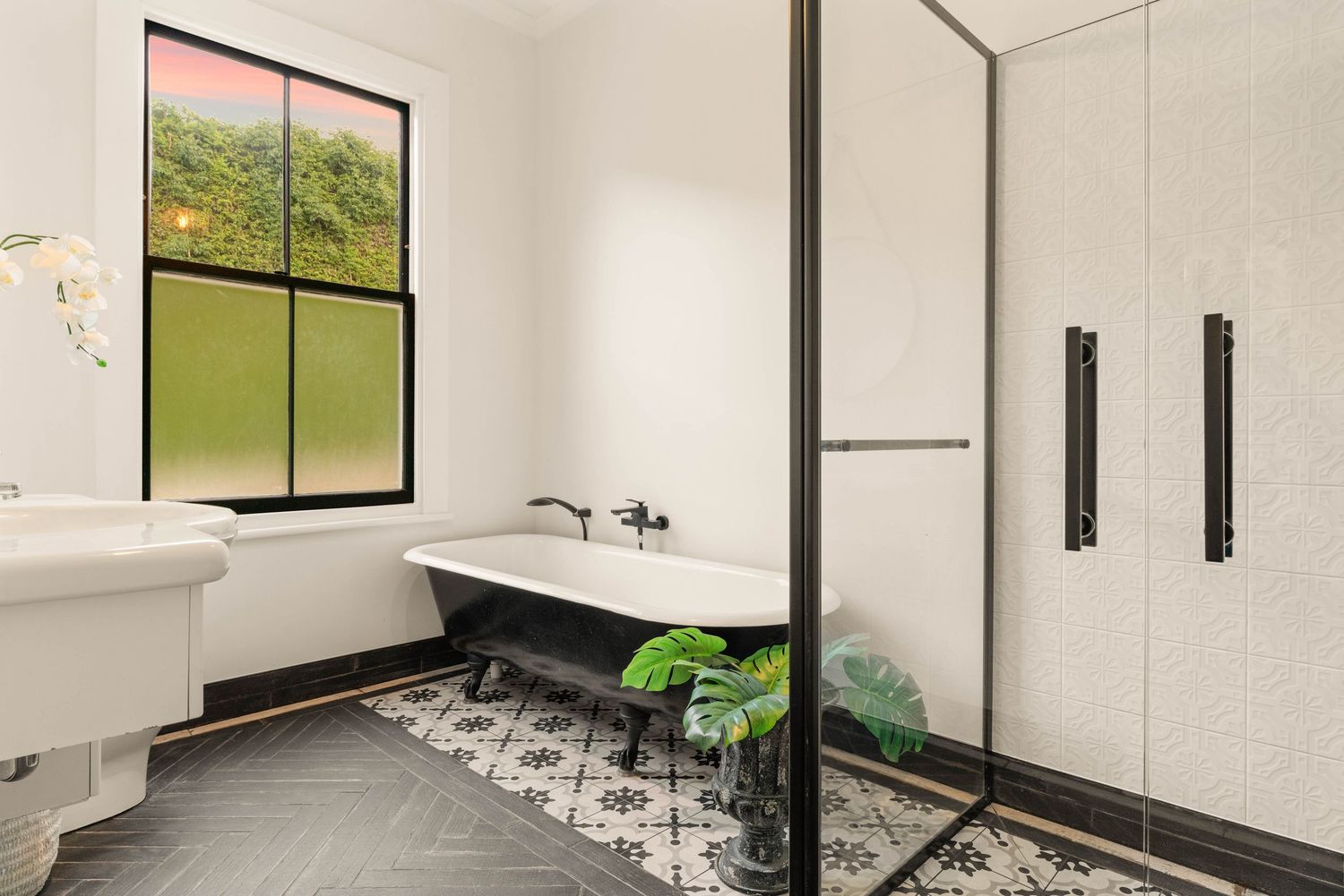 Modern bathroom with black and white geometric floor tiles, white walls, and built-in storage cabinets.