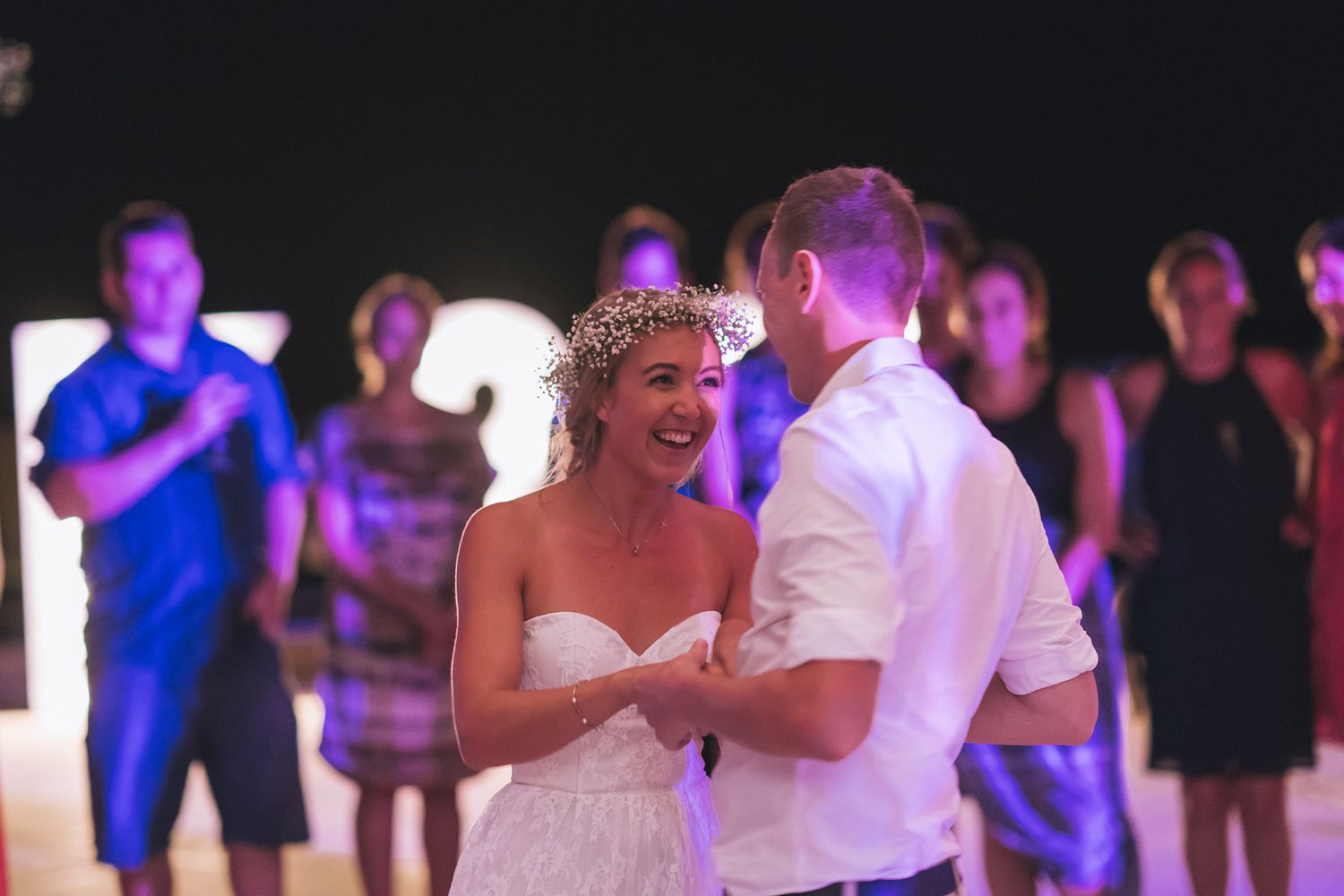 A wedding couple dances together on an illuminated dance floor during their reception celebration.