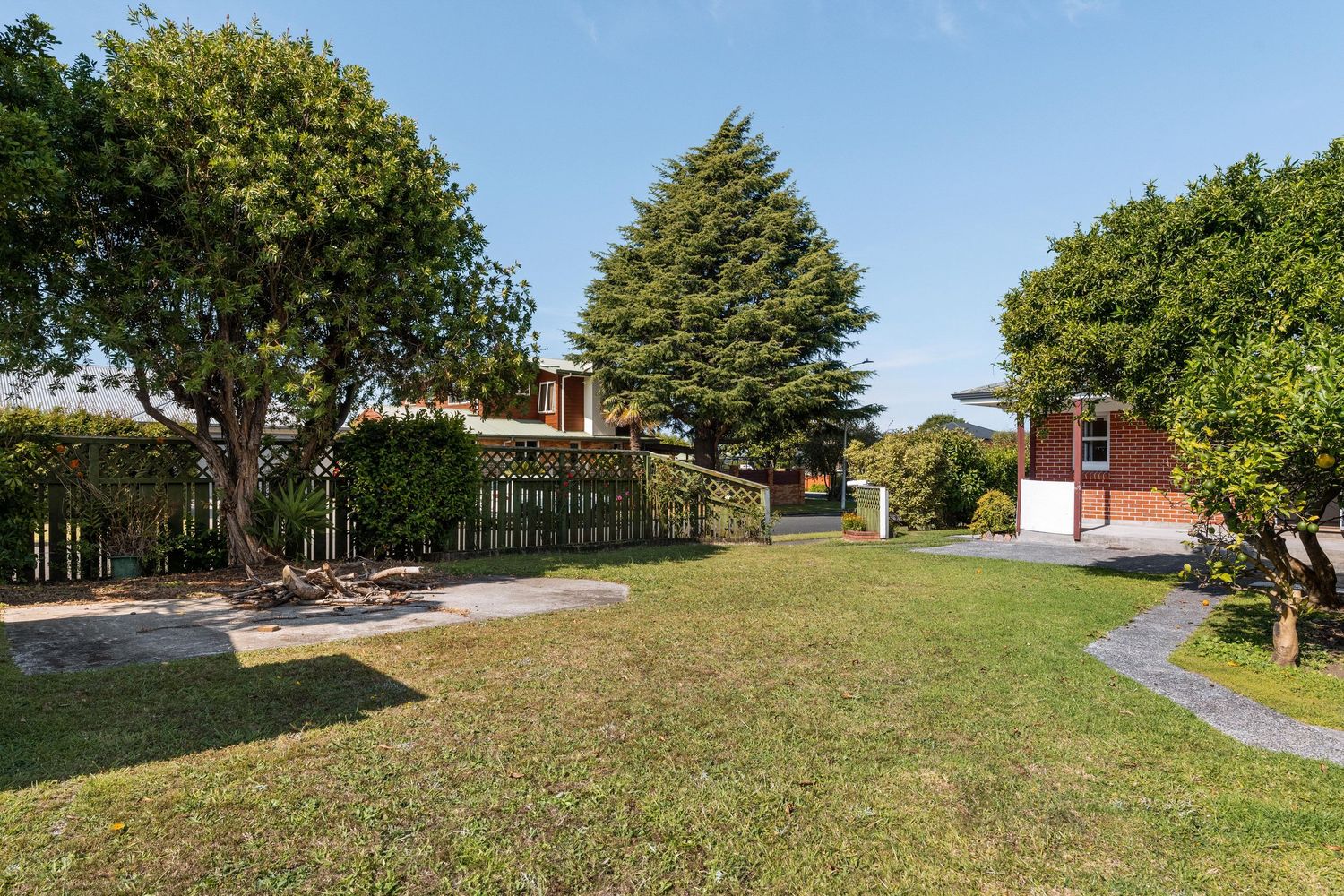 Panoramic view of a large backyard with green lawn and mature trees.