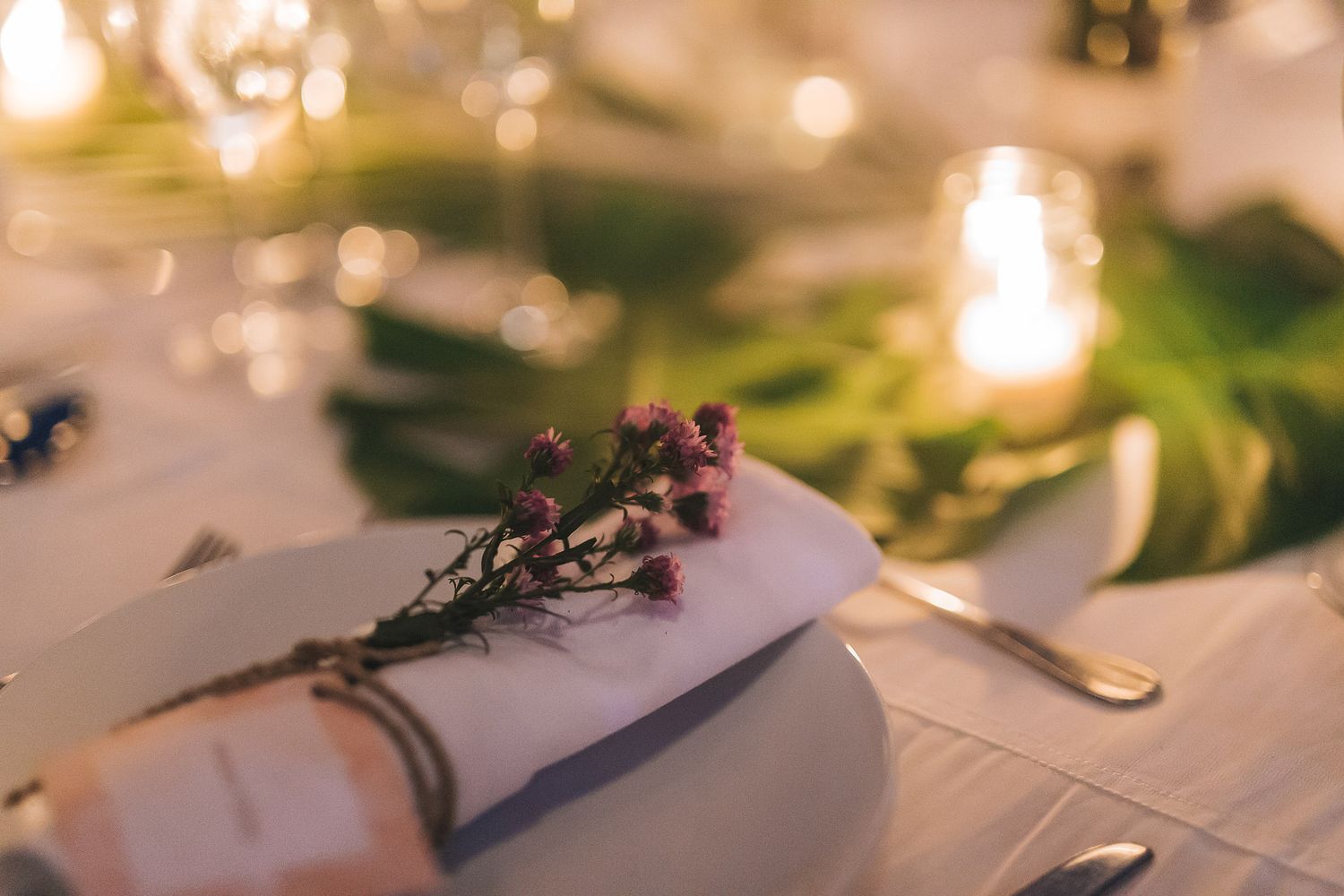 Elegant wedding reception table setting with soft candlelight and floral decorations.