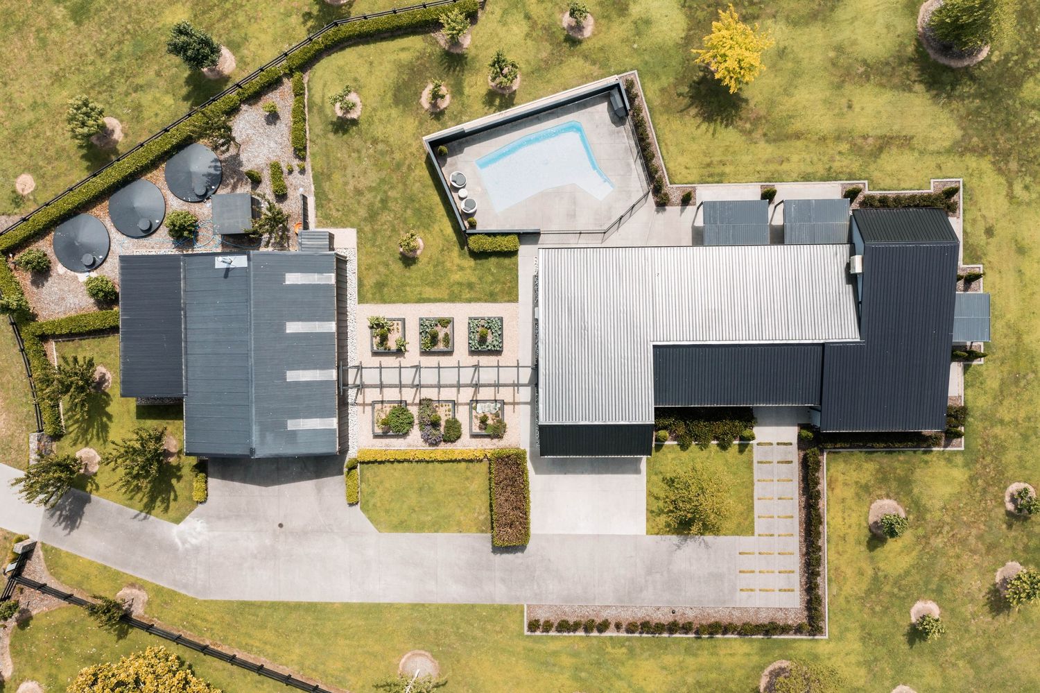 Birds-eye view showing the geometric layout of a contemporary house with grey roof and paved driveway.