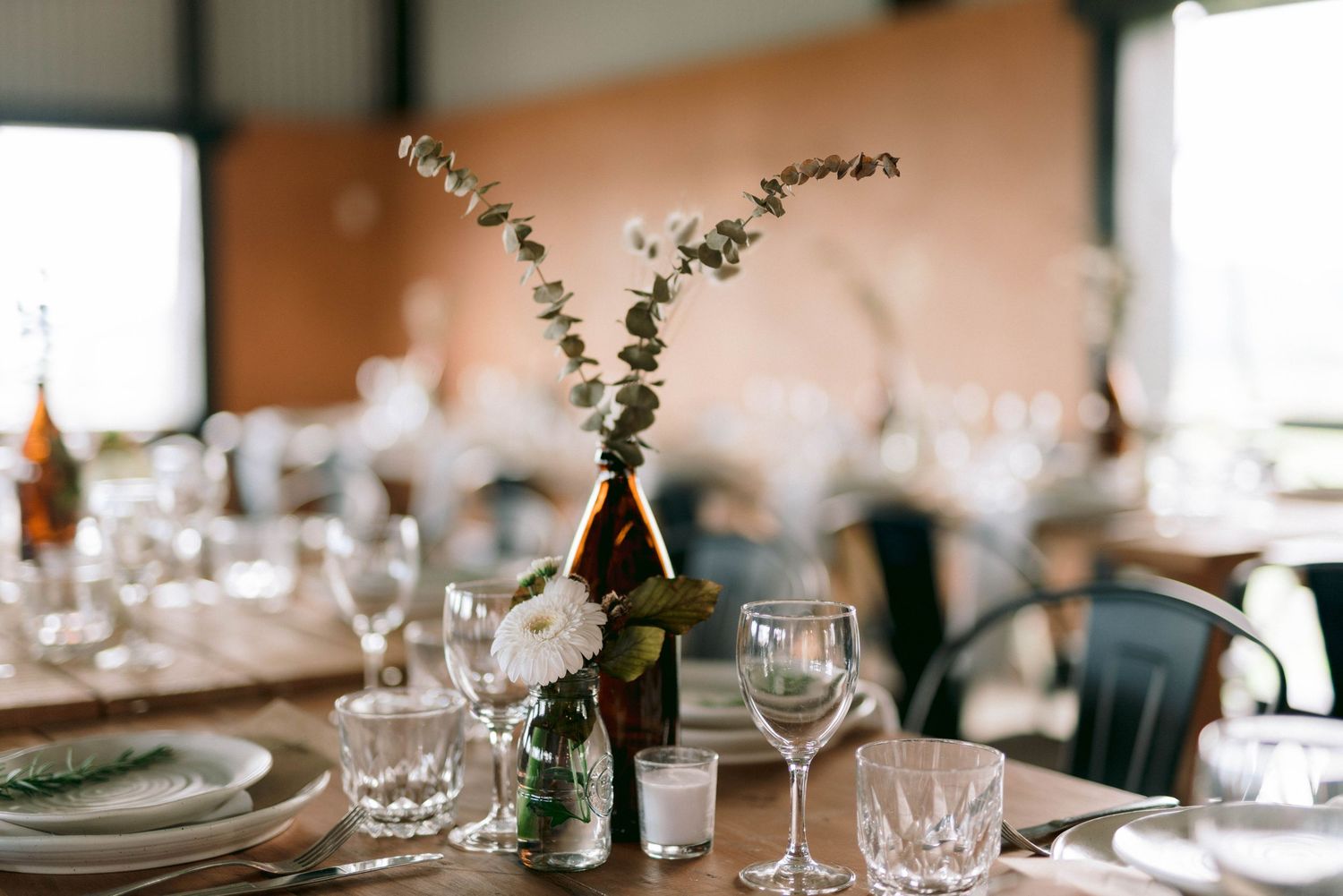 Elegant table setting with minimalist floral centerpiece and wine glasses at wedding reception.