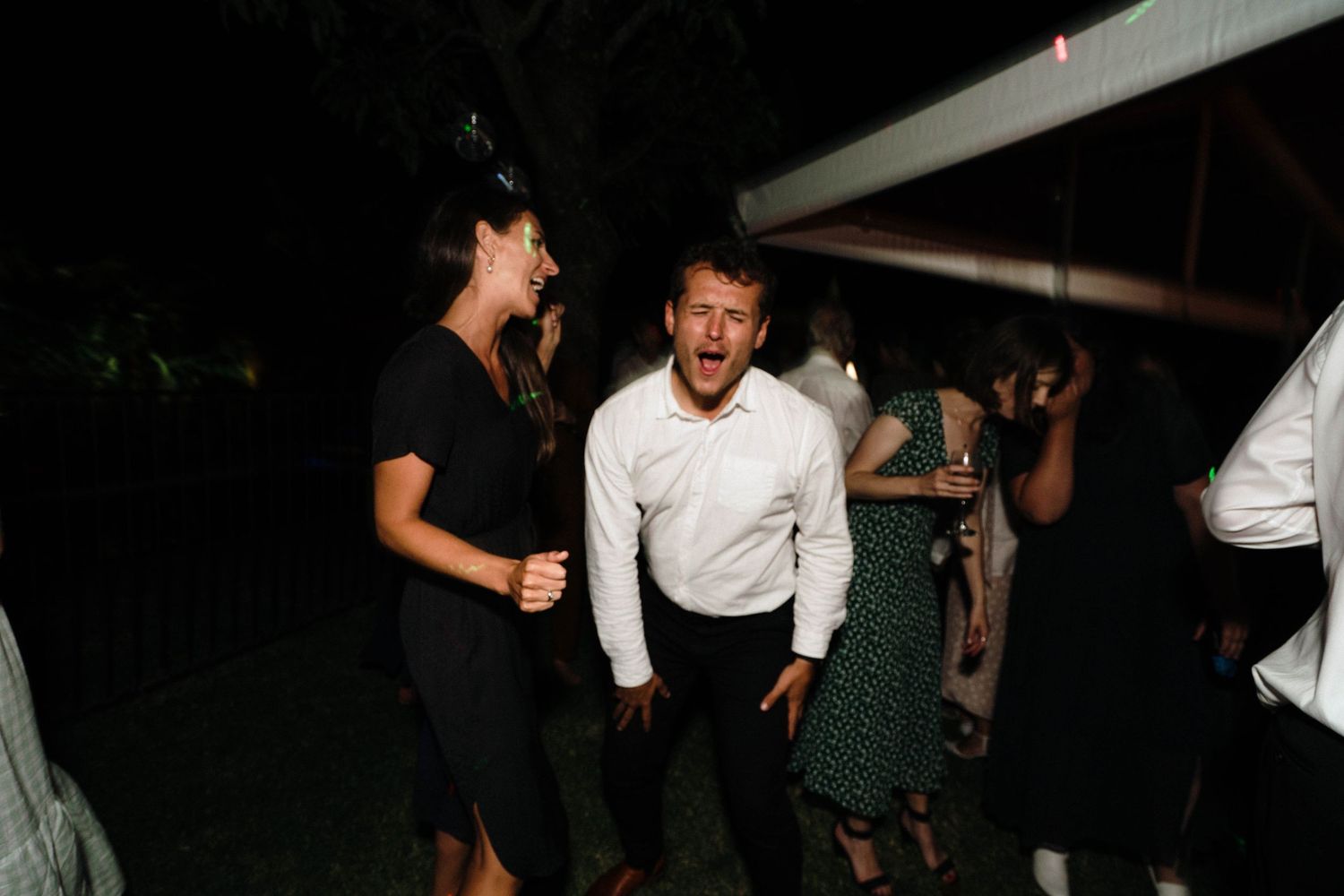 Wedding guests dancing and celebrating during an evening reception party.