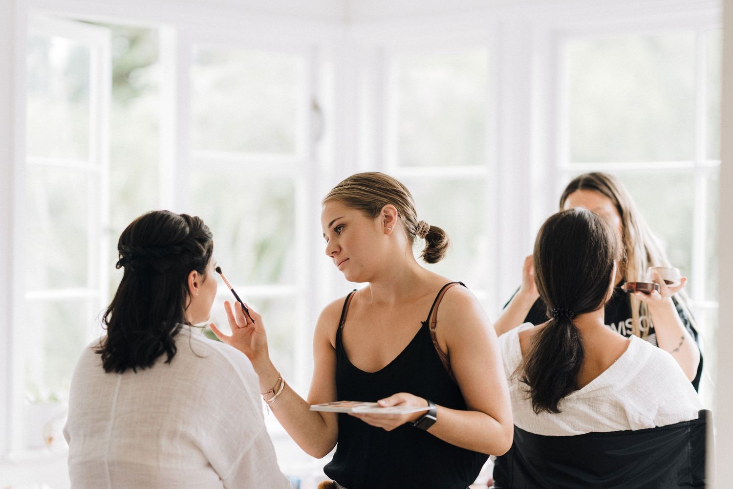 Bridesmaids in matching black dresses prepare for a wedding celebration.
