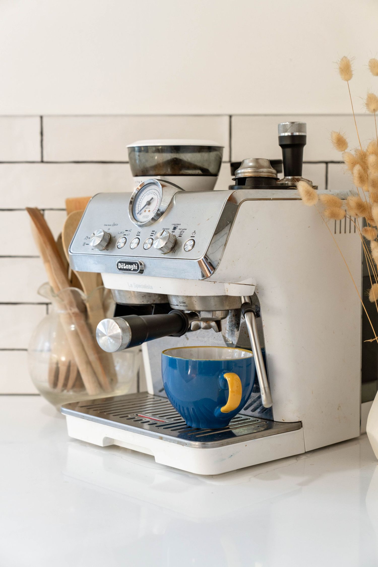 Modern espresso machine and coffee making equipment on white counter top.