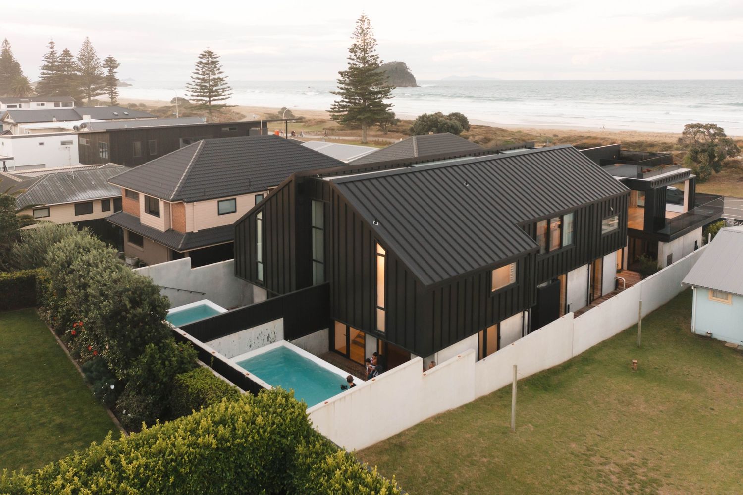Modern black coastal home with swimming pool features dramatic angular architecture and ocean views.