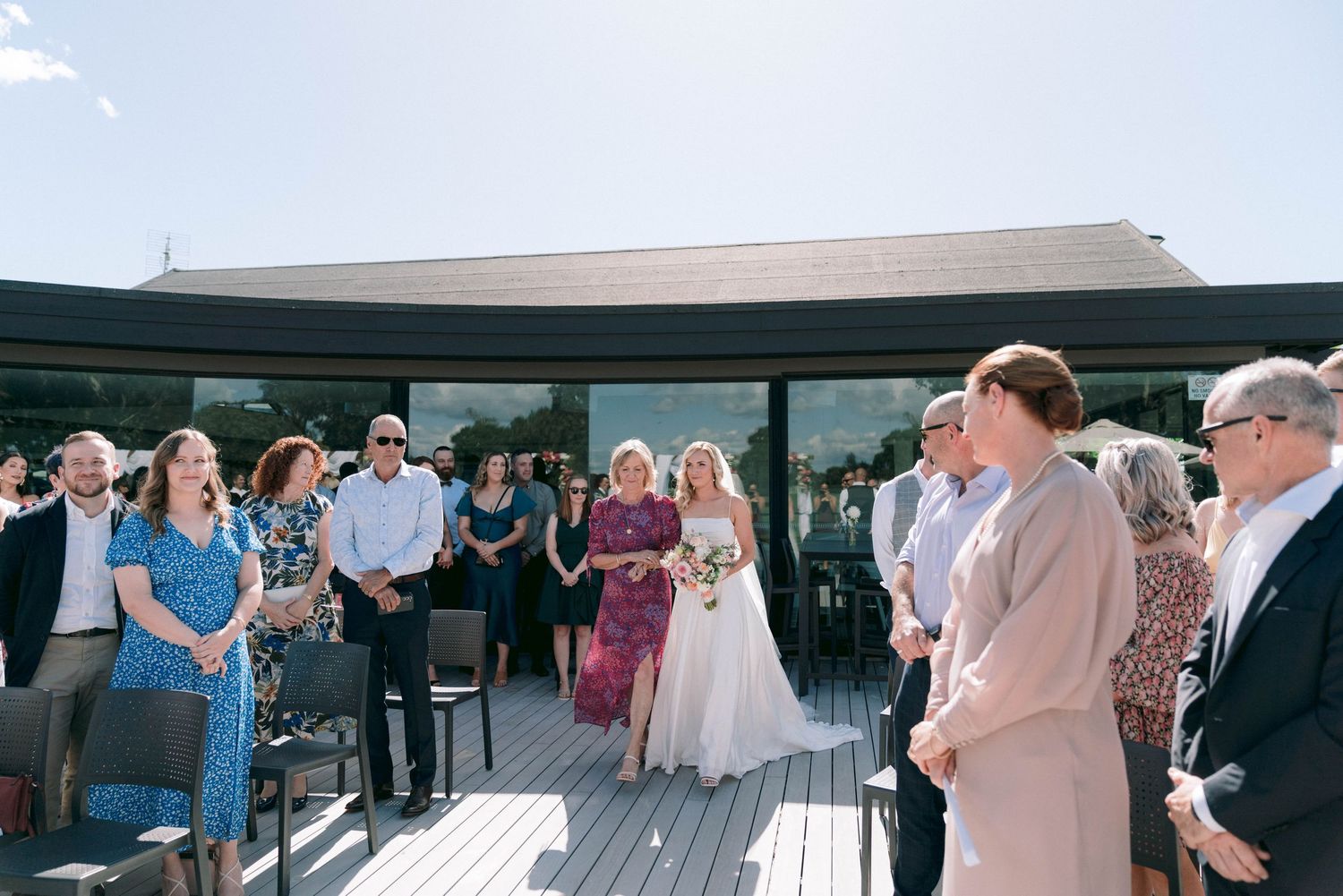Outdoor wedding reception with guests mingling under a covered patio area.