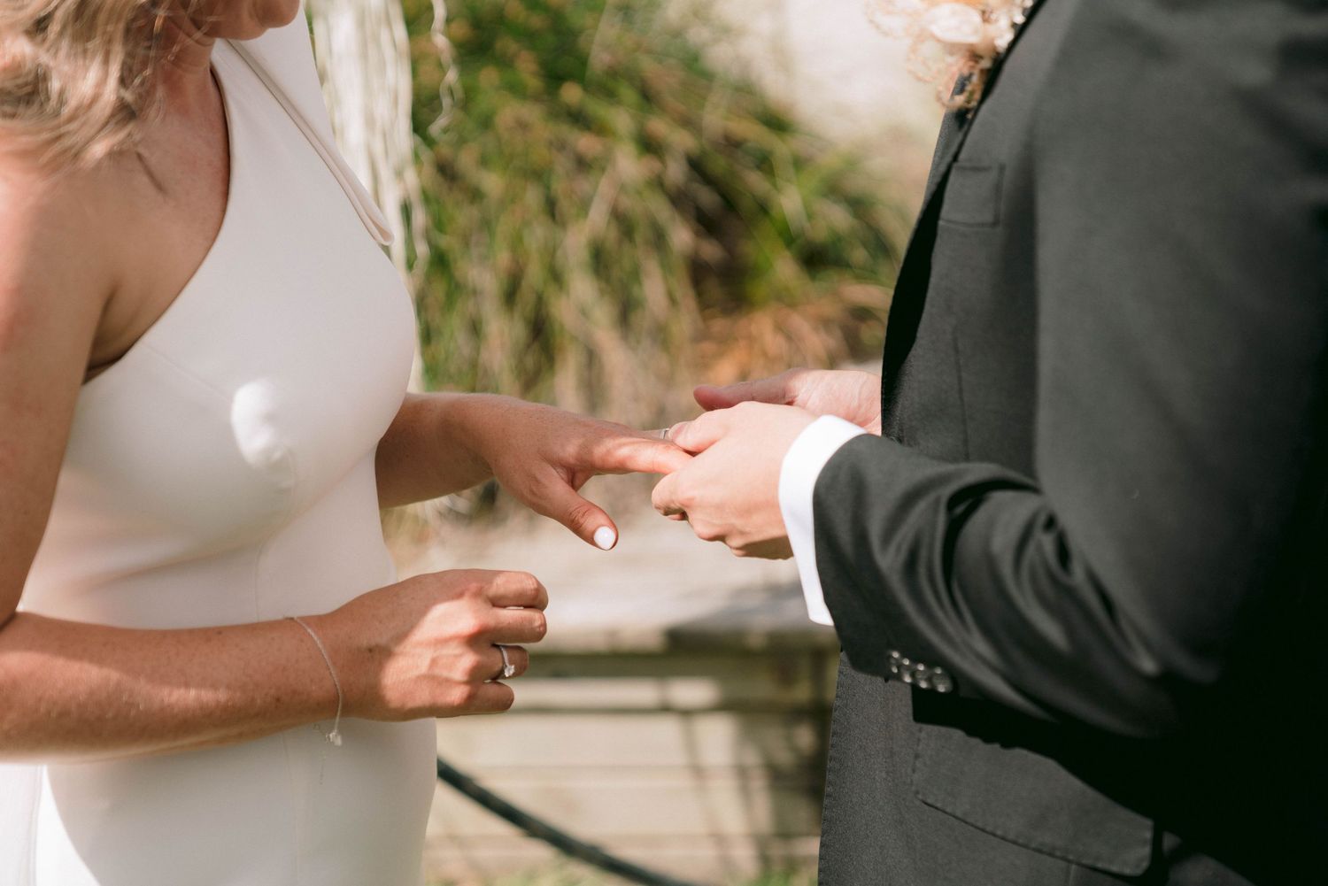 Close-up view of hands exchanging wedding rings during an intimate ceremony.