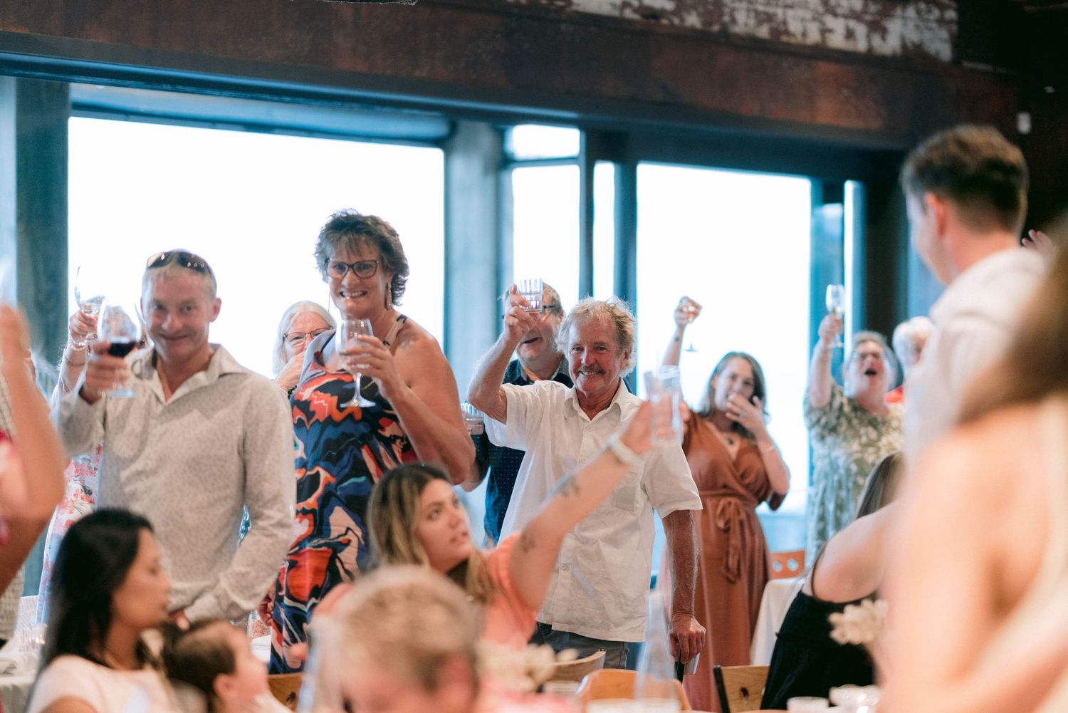 Wedding reception celebration with guests toasting and enjoying festivities indoors.