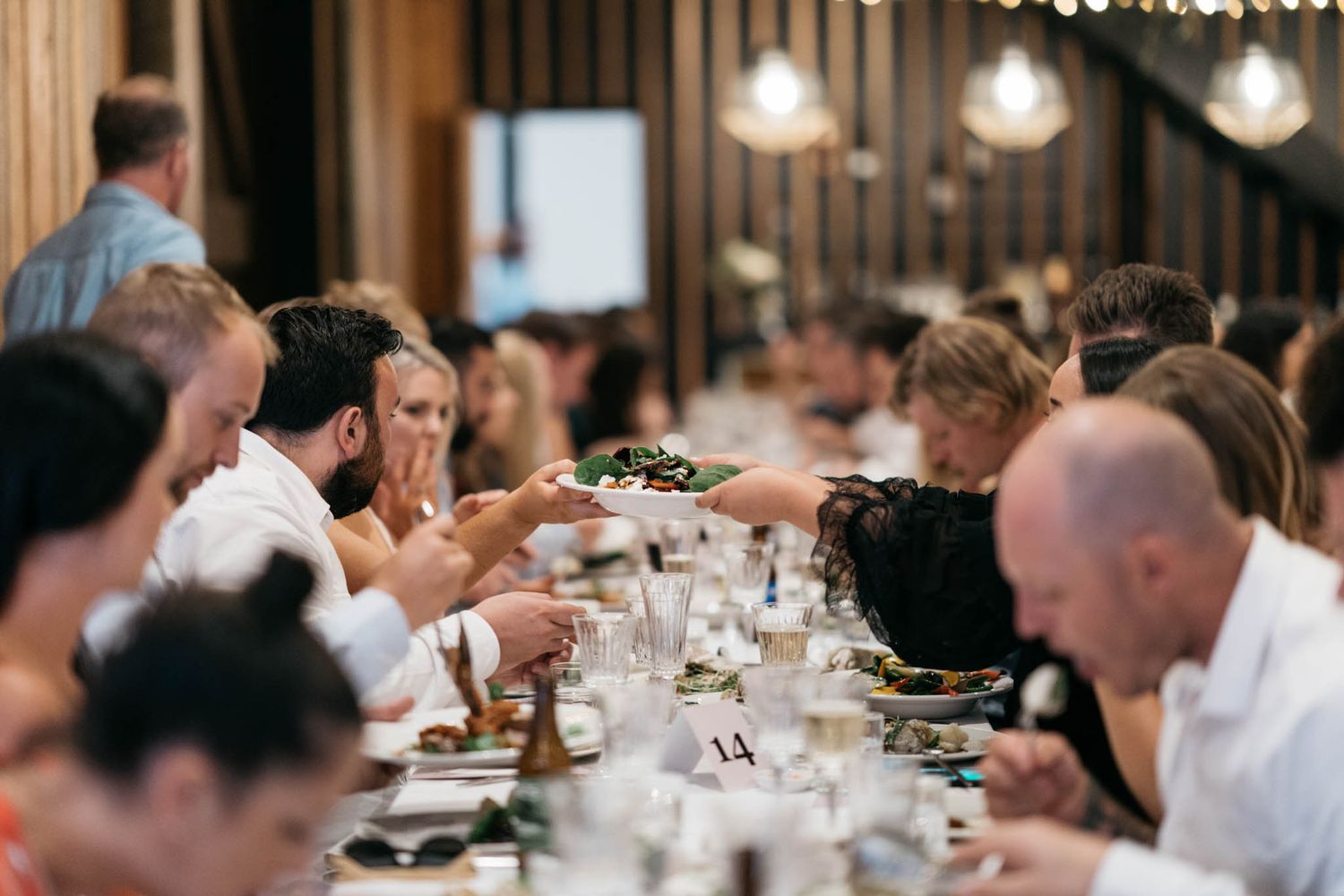 Guests seated at elegant dining tables in a dimly lit restaurant enjoy a formal dinner gathering.