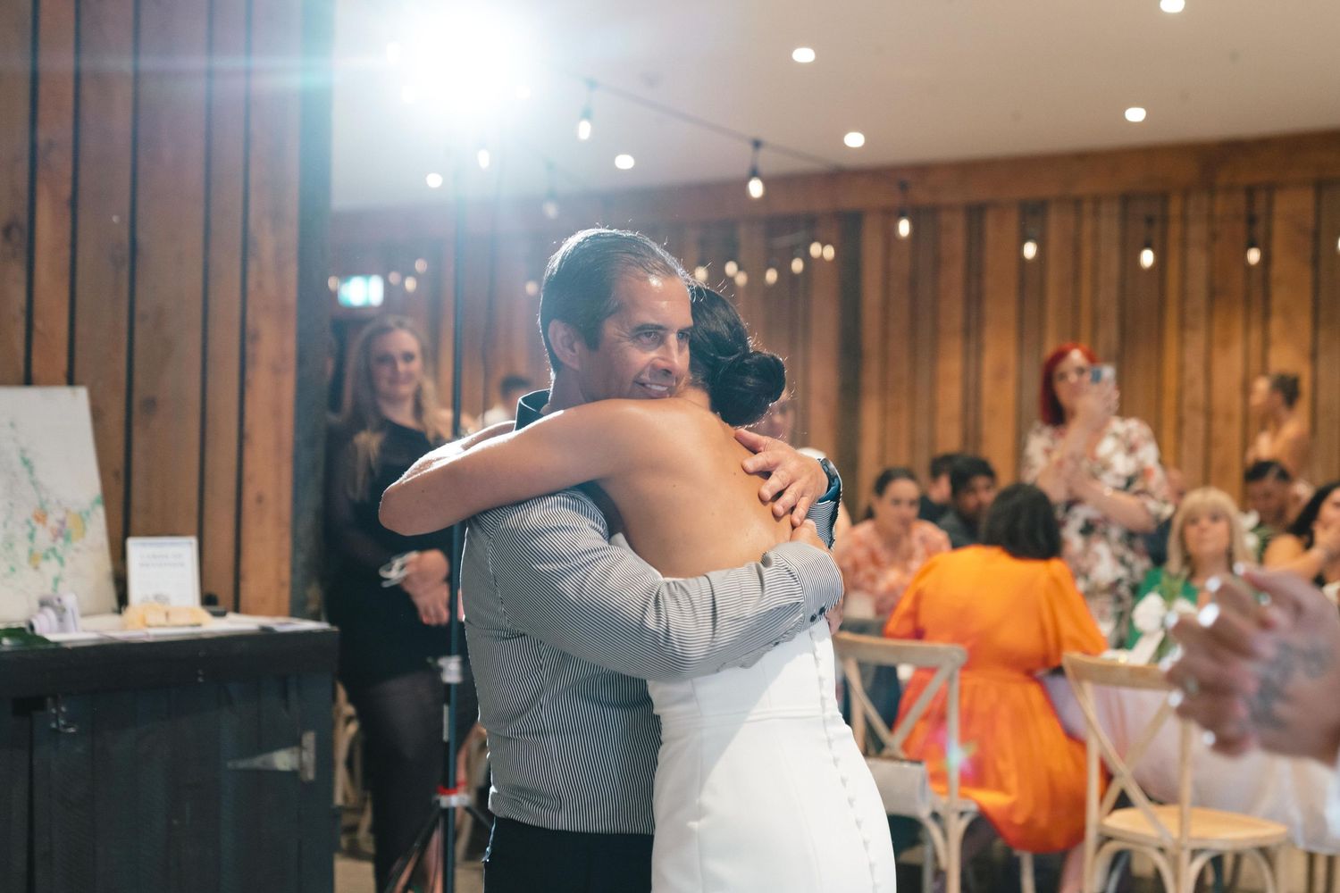 A tender moment during a wedding reception in a warmly lit indoor venue.