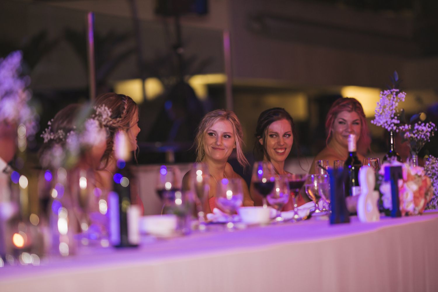 Wedding reception table scene with soft purple lighting and wine glasses creating an ambient atmosphere.