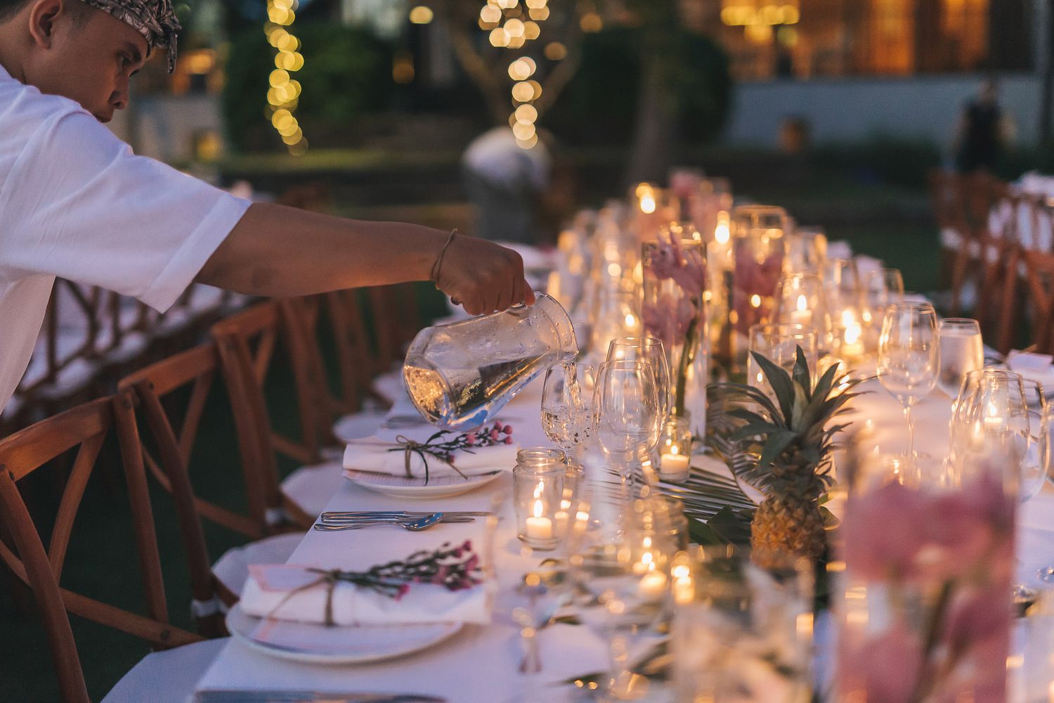 Intimate wedding dinner table settings with glowing candles and rustic wooden chairs.