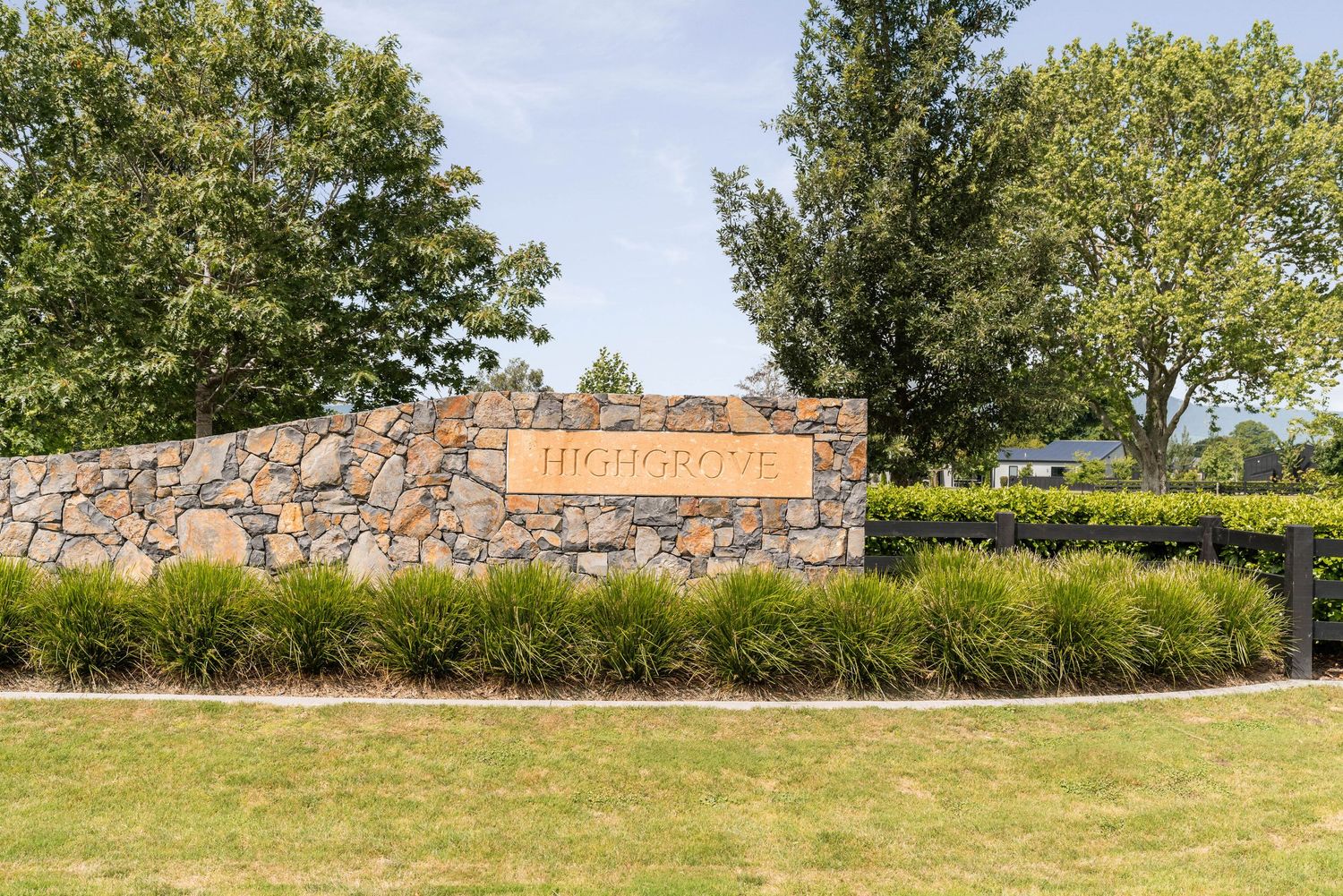 Stone entrance sign with landscaping and shrubs at a residential development.