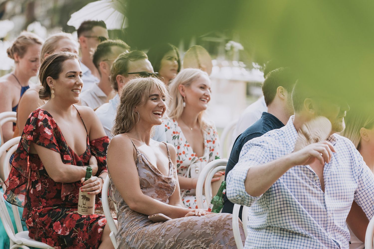 Group of guests in casual summer attire enjoying refreshments and conversation at an outdoor gathering.