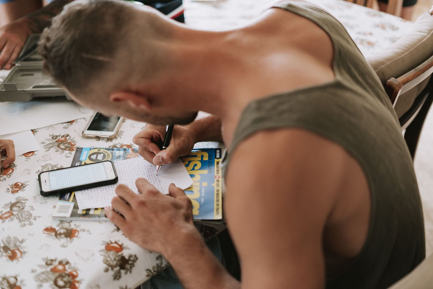 Someone sketching or drawing at a table covered with art supplies and papers.
