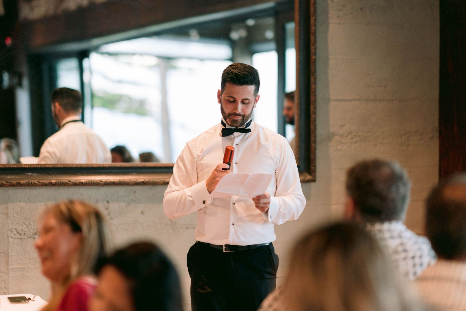 Speaker addresses wedding guests during reception dinner event.