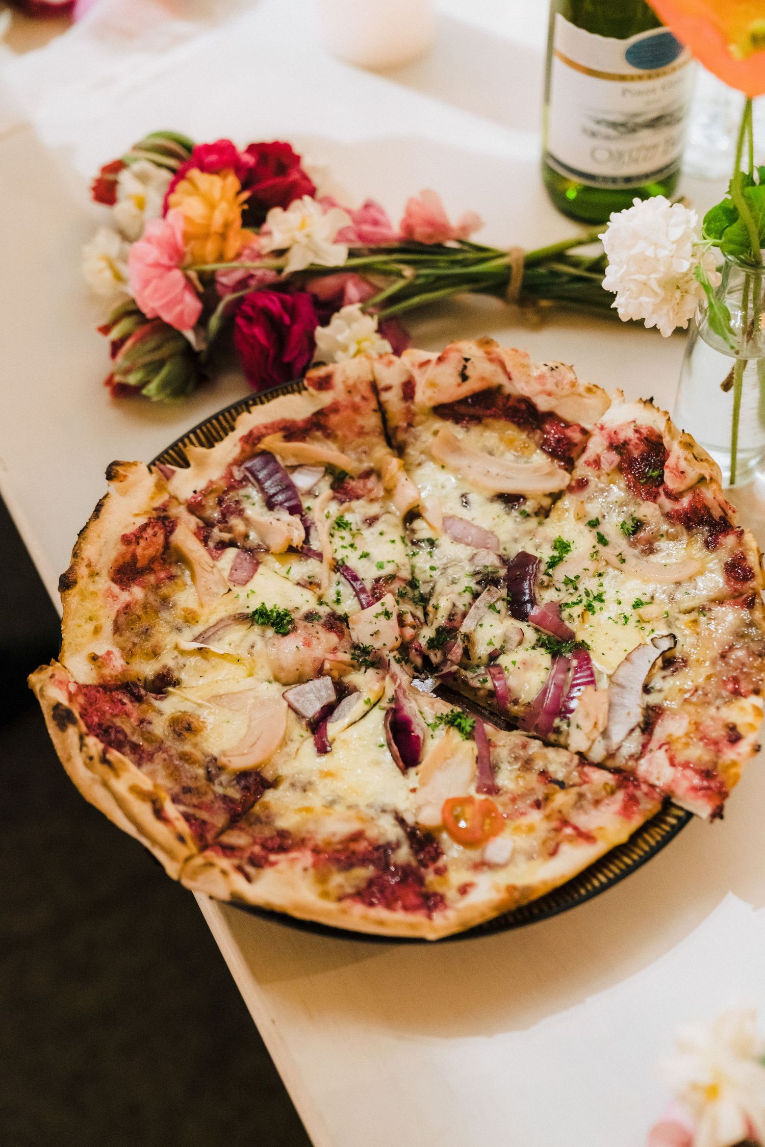 Gourmet wood-fired pizzas with melted cheese and fresh toppings served at a wedding reception.