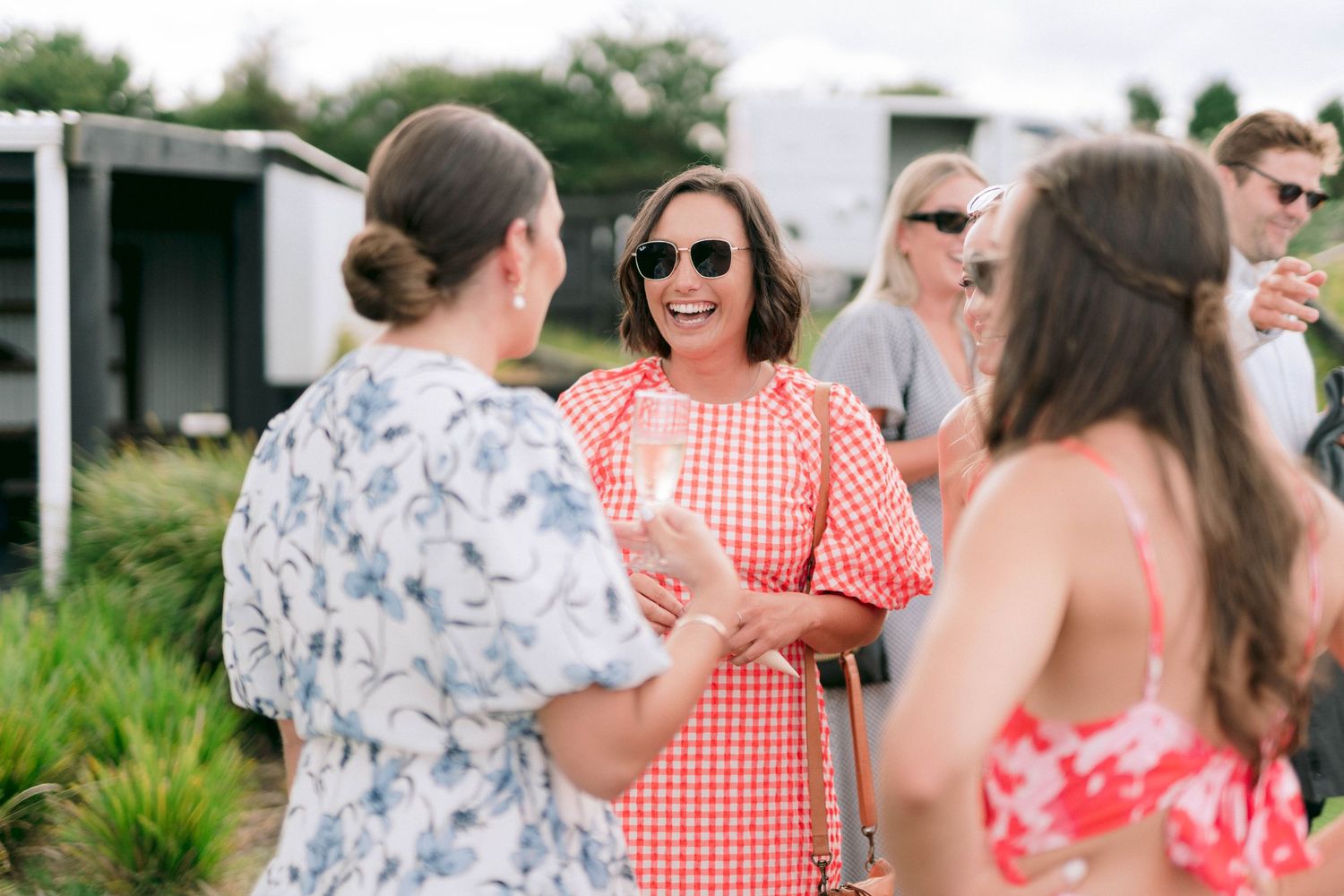 Wedding guests engage in casual conversation at an outdoor reception.