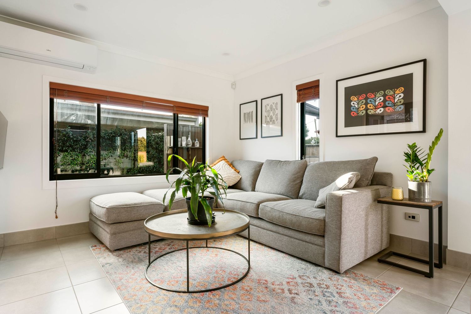 Contemporary living room with gray sectional sofa, round coffee table, and large windows bringing in natural light.