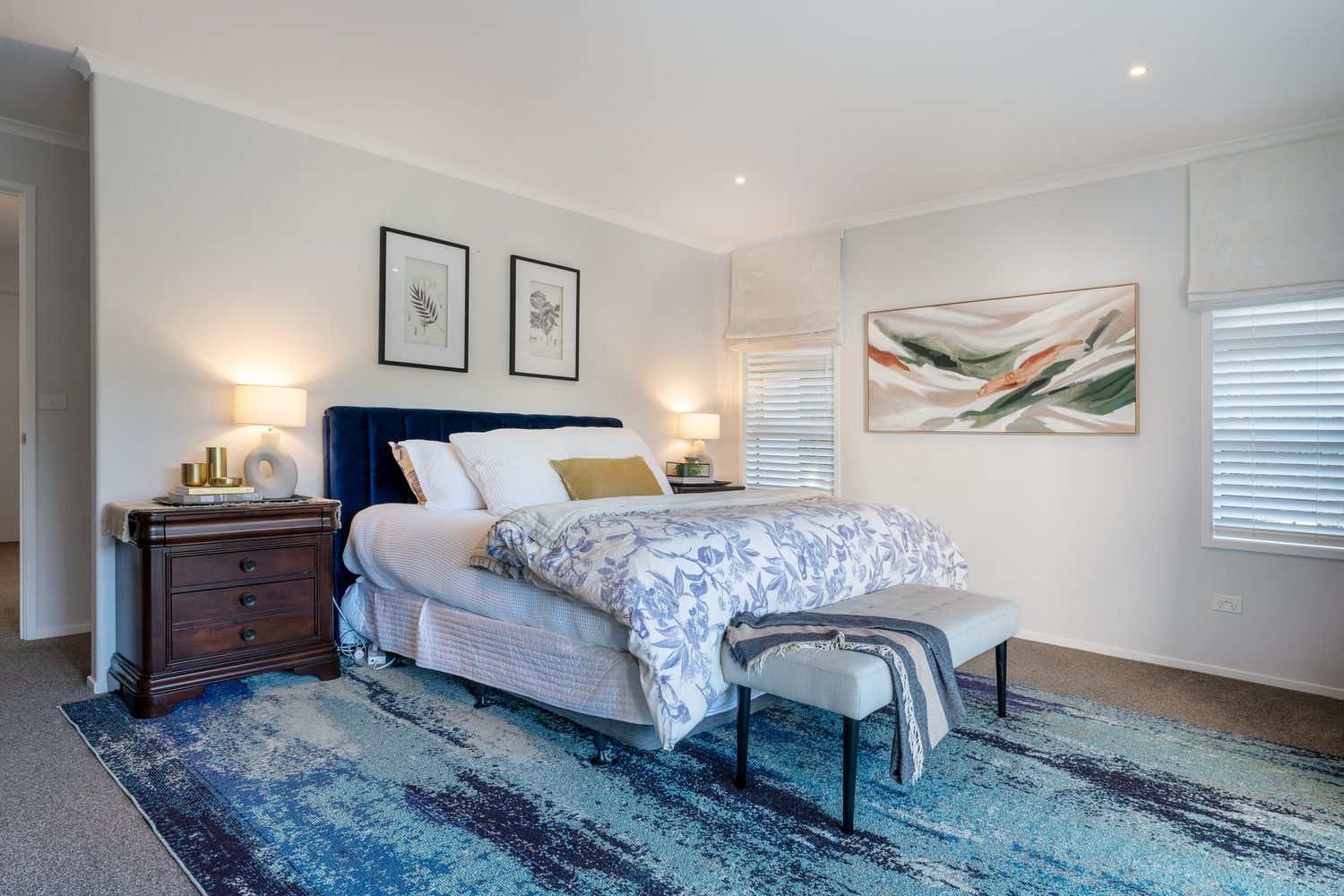 Modern bedroom with blue area rug, upholstered bed, and contemporary wall art.