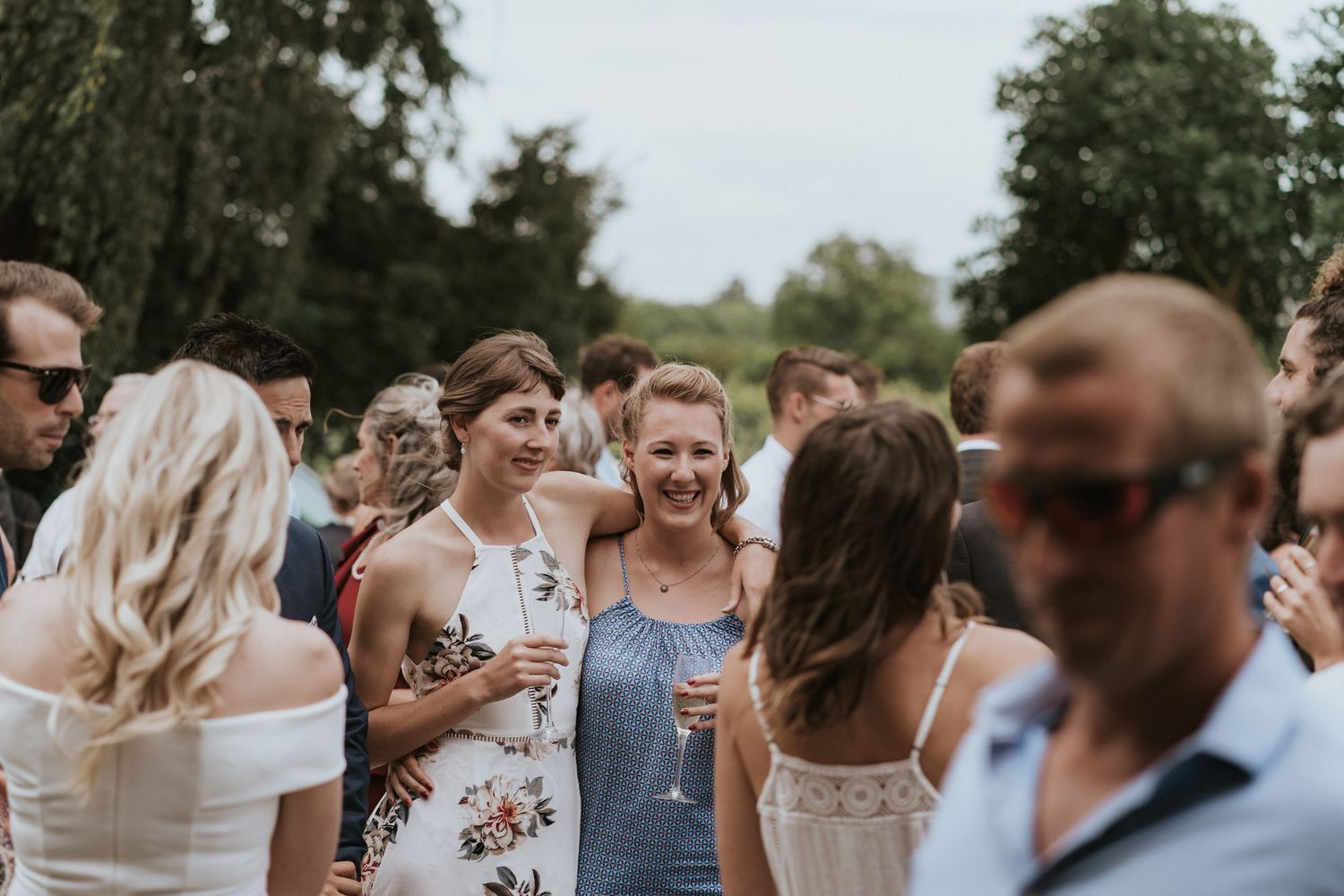 Wedding guests enjoying an outdoor reception with drinks and conversation during a summer celebration.
