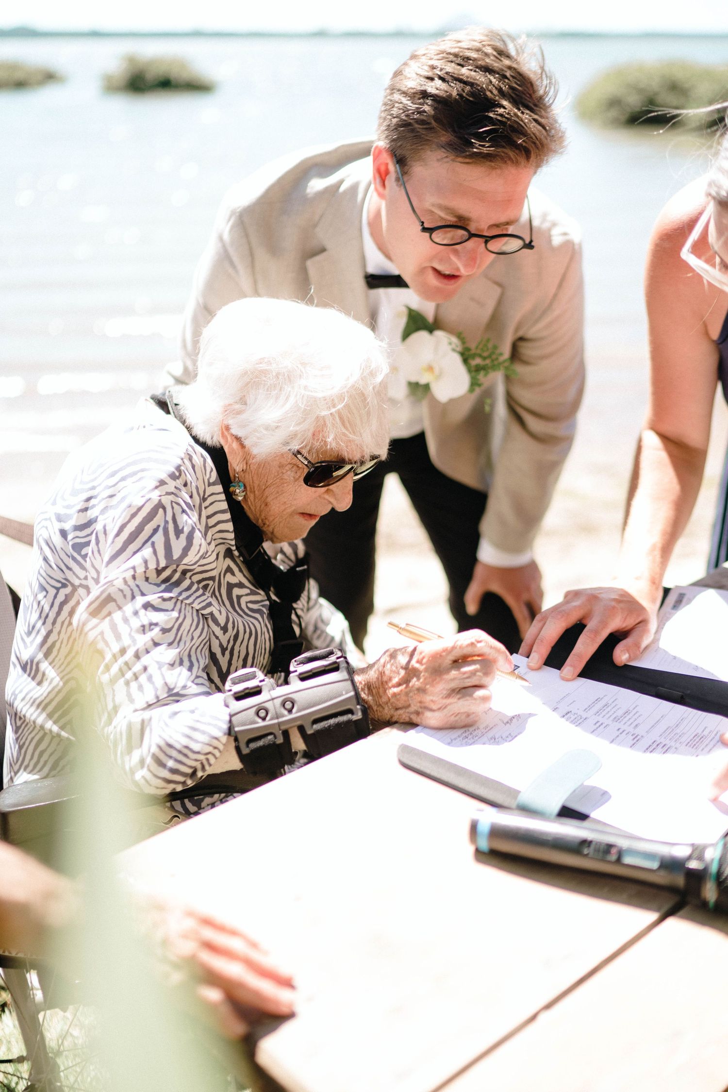 Guests signing a wedding guestbook with pens at a reception table.