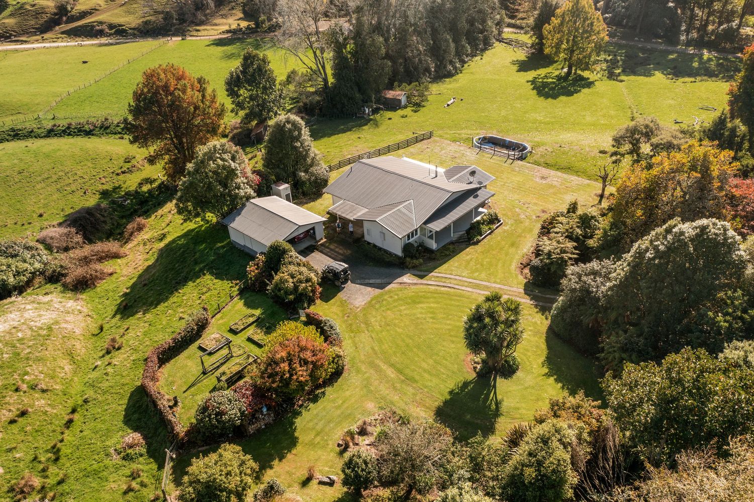 Aerial view of a ranch house nestled in lush green countryside surrounded by autumn trees.